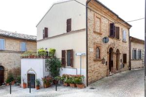 an old building with potted plants on a street at B&B La Finestra Sul Campanile in Montecosaro
