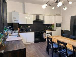 a kitchen with white cabinets and a wooden table at Deluxe Huge Detached House with Parking, sleeps up to 30 people, 2m from Liverpool City Centre in Liverpool