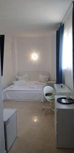a white bedroom with a bed and a chair at Leul De Mare in Eforie Sud