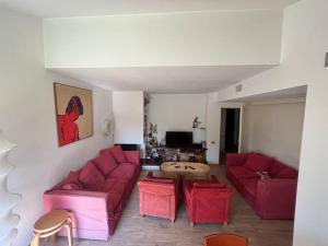 a living room with two red couches and a table at Casa fronte lago con piscina in Angera