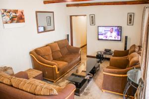 a living room with two couches and a tv at Stone Camp Naivasha in Naivasha