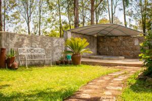 un jardín con un banco y una sombrilla grande en Stone Camp Naivasha en Naivasha