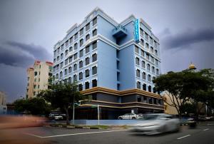 a tall blue building with a car in front of it at Hotel 81 Premier Princess in Singapore