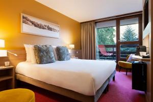 a hotel room with a bed and a large window at SOWELL HOTELS Mont Blanc et SPA in Saint-Gervais-les-Bains