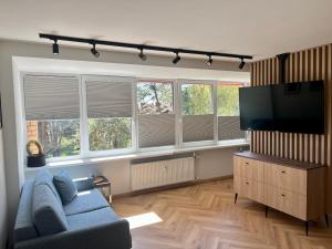 Apartamentai KOPOS Nidoje في نيدا: غرفة معيشة مع أريكة زرقاء وتلفزيون بشاشة مسطحة