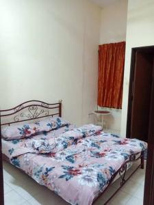 Bett mit Blumendecke in einem Schlafzimmer in der Unterkunft Salak Indah Homestay KLIA/KLIA2 in Sepang