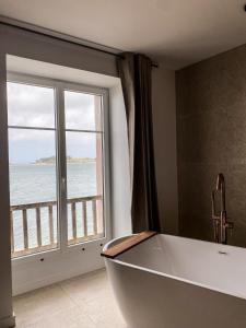 uma banheira na casa de banho com uma grande janela em ILE CEZON - Duplex de luxe avec magnifique vue mer em Landéda