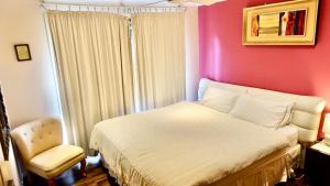 um quarto com uma cama branca e uma parede rosa em TL Warmest Homestay em Gold Coast