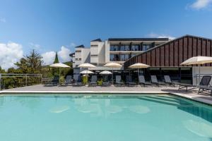 a swimming pool with chairs and umbrellas in front of a building at Hotel Ad Turres in Crikvenica