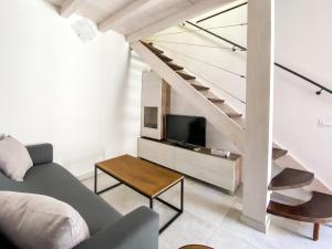 ein Wohnzimmer mit einem Sofa, einem TV und einer Treppe in der Unterkunft La Casetta - Appartamento Centro Storico Albenga in Albenga