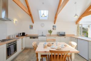 a kitchen with a wooden table and chairs in a room at Cobblestone Cottage in Penzance