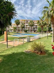 a swimming pool in a park with palm trees and a building at Planta baja Playa Sol 2 in Denia