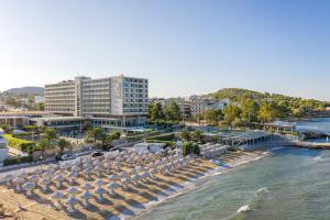 a beach with chairs and umbrellas next to the water at Divani Apollon Palace & Thalasso in Athens
