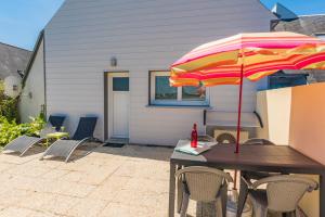 a wooden table with an umbrella on a patio at gite steir in Penmarch
