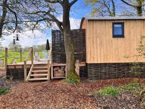 a wooden cabin with a staircase next to a tree at Cattlestone Farm in West Chiltington