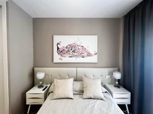 1 dormitorio con 1 cama con 2 mesitas de noche y una pintura en Tropical y Lujoso Complejo, en Oropesa del Mar