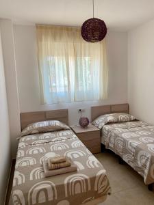 a bedroom with two beds and a window at Planta baja Playa Sol 2 in Denia