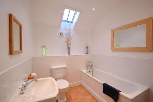 a bathroom with a tub and a toilet and a sink at Cobblestone Cottage in Penzance