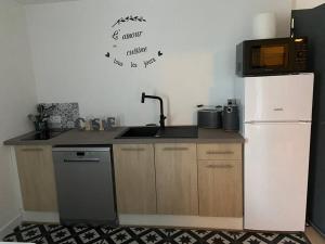 uma cozinha com um frigorífico, um lavatório e um micro-ondas em Bel Appartement 1er étage t2 4 pers avec cour les cocons de Madenn em Lamballe