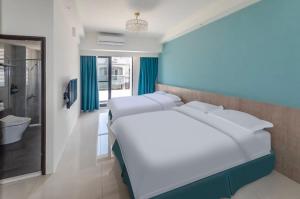 1 dormitorio con 2 camas blancas y baño en 春雨漫居 Spring Rain Hostel, en Meishan