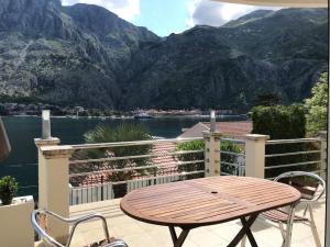 a wooden table and chairs on a balcony with mountains at Two bedroom Apartment in Kotor Bay in Muo