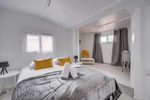 a white bedroom with a large bed with yellow pillows at La Casa Bohème - Superbe maison avec parking privé in Bordeaux