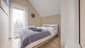 a white bedroom with a bed and a window at Apartamenty Sun & Snow Kuracyjna in Jastrzębia Góra