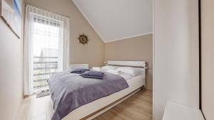 a white bedroom with a bed and a window at Osiedle Kuracyjna, Sun & Snow in Jastrzębia Góra