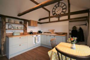 a kitchen with a table and a clock on the wall at The Calf Shed at Broxhall Farm in Canterbury