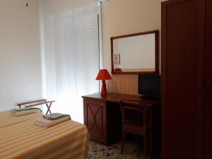 1 dormitorio con cama, escritorio y espejo en Hotel Geppi en Pietra Ligure