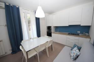 uma cozinha com armários brancos e uma mesa e cadeiras brancas em Residence Verdena appartamento 02 em Rosolina Mare
