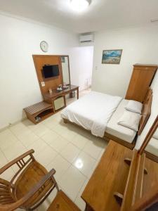 a bedroom with a bed and a desk and a television at Hotel Besar Purwokerto in Purwokerto