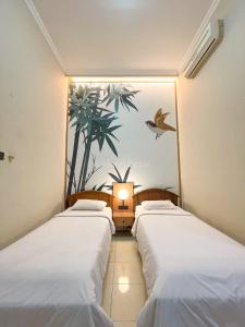 2 letti in una camera con un dipinto sul muro di Hotel Besar Purwokerto a Purwokerto
