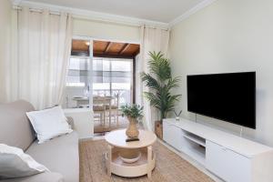 un soggiorno bianco con TV e divano di EDEN RENTALS Ocean Poris Pearl a Poris de Abona