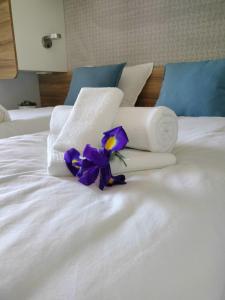 Una cama blanca con toallas y flores púrpuras. en Medeja, en Osor