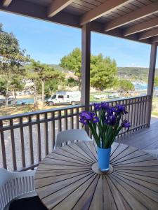 a table with a vase of purple flowers on a porch at Medeja in Osor