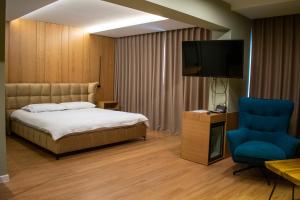 a bedroom with a bed and a tv and a blue chair at Bocca Hotel Korce in Korçë