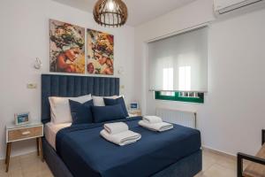 a bedroom with a blue bed with towels on it at Vasilikis Apartments in Daratso