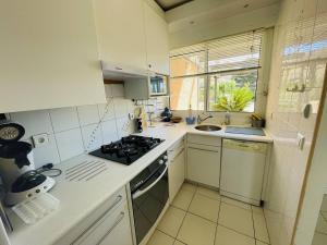 uma cozinha branca com um fogão e um lavatório em Appartement Cap d'Agde, 4 pièces, 8 personnes - FR-1-723-27 em Bizanos