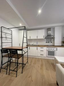 アドラにあるApartamentos La Hormiga Deluxeの白いキャビネット、テーブルと椅子付きのキッチンが備わります。