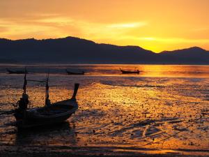 a group of boats on the beach at sunset at Modern Sunset Sea House Lam Sai in Ko Yao Noi