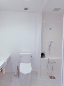 a white bathroom with a toilet and a shower at Nakijin Resort Guest House in Nakijin