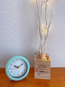 un reloj sentado en una mesa junto a un jarrón en Nakijin Resort Guest House, en Nakijin
