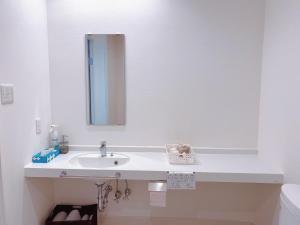 a white bathroom with a sink and a mirror at Nakijin Resort Guest House in Nakijin