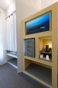 Habitación de hotel con TV de pantalla plana en la pared en Executive Inn Boutique Hotel, en Brindisi
