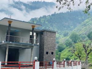 a building with a balcony with a mountain in the background at River Garden Hotel and Resort in Naran