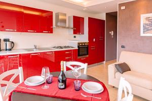 una cocina con armarios rojos y una mesa con copas de vino en BELLA VITA Residence, en Gravedona