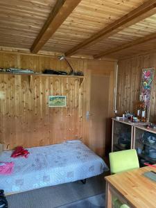 - une chambre avec un lit et un mur en bois dans l'établissement Behagliches Chalet mit Kaminofen umgeben von Natur, à Glarus