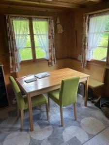- une table et des chaises en bois dans une chambre avec fenêtres dans l'établissement Behagliches Chalet mit Kaminofen umgeben von Natur, à Glarus