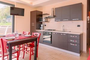 een keuken met een tafel en rode stoelen in een kamer bij BELLA VITA Residence in Gravedona